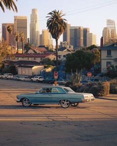 an old car is parked on the street in front of a large cityscape