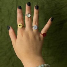 a woman's hand with three different rings on it and two buttons in the middle