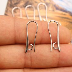 pair of small silver earrings on finger