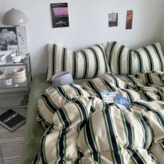 a bed with green and white striped comforter next to a wall with pictures on it