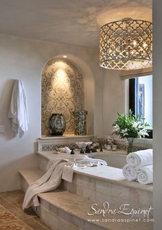 a bath room with a large tub and a chandelier hanging from the ceiling