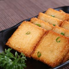 some food is on a black plate with green garnish