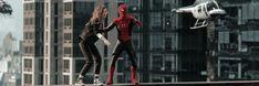 two people in spider - man suits are standing on a ledge with a helicopter flying over them