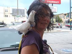 a woman is holding a bird on her shoulder