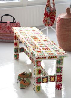 a bench made out of crocheted fabric with shoes on the floor