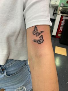 a woman's arm with two butterflies tattooed on the left side of her arm