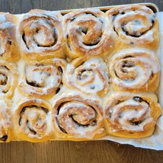 a tray filled with cinnamon rolls sitting on top of a wooden table