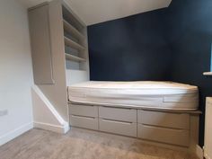 there is a bed in the corner of this room with built - in shelving