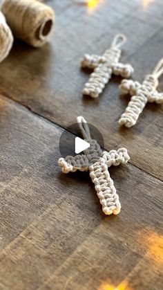 two crocheted crosses sitting on top of a wooden table next to twine