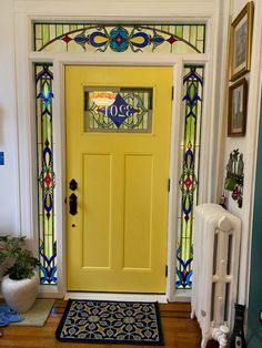 a yellow front door with stained glass on the top and side panels over the bottom