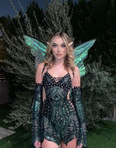 a woman in a bodysuit with wings on her head and one leg, standing outside at night