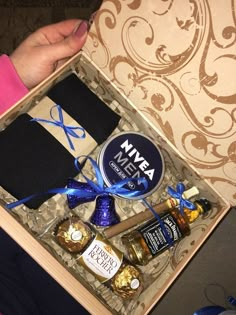 a person is holding a wine and chocolates in a gift box with a blue ribbon