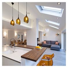 a kitchen with an island and skylights in the ceiling, next to a living room