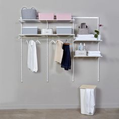 a white shelf with clothes and baskets on it