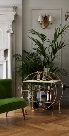 a green chair sitting next to a table filled with bottles and glasses on top of it