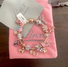 the charm bracelet is sitting on top of a pink cloth