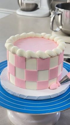 a pink and white cake sitting on top of a blue plate with a spatula