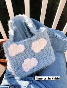 someone is laying down on their stomach wearing a hand knitted blue purse with white hearts