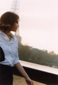 a woman is walking down the street with her suitcase in hand and looking at the eiffel tower