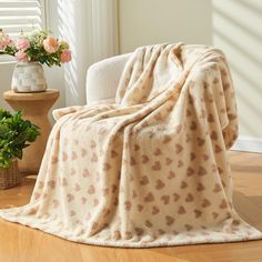 a white chair with a blanket on it next to a potted plant and window