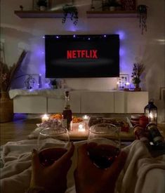 two people toasting wine glasses in front of a television with the netflix logo on it