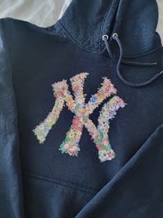 Vibrant and beautiful New York Flower Hoodie! Navy Aethstetic, Stitch Work Hoodie, Fabric Sweatshirt Design, New York Essentials, Embroidery Hoodies Inspiration, New York Yankees Hoodie, How Lucky Are We Hoodie, Cricket Hoodie Ideas, Embroidery Designs On Hoodies