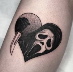 a black and white tattoo with a skull in the shape of a heart holding a knife