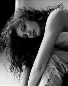 a black and white photo of a woman sitting on the floor with her hands behind her head