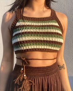 a close up of a person wearing a crop top and skirt with tassels