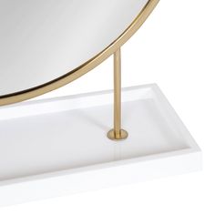 a mirror sitting on top of a white counter next to a metal pole with a gold handle