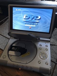 a cd player sitting on top of a wooden table next to a laptop computer screen