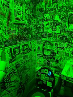 a green bathroom with graffiti all over the walls