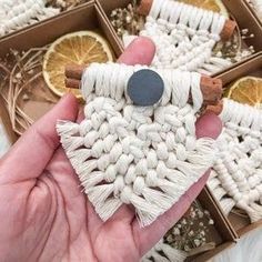 a hand is holding an ornament made out of cotton and cinnamon sticks in a box