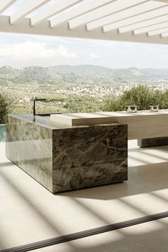 an outdoor kitchen with marble counter tops and stainless steel appliances in the foreground, overlooking a valley