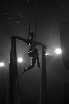 a woman is performing aerial acrobatic tricks in the dark