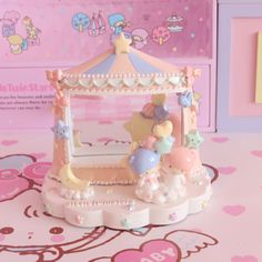 a small toy carousel on a table with hello kitty wallpaper