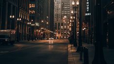 an empty city street at night with tall buildings