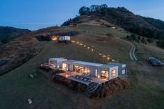 an aerial view of a house on a hill at night with lights strung from the roof