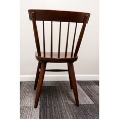 a wooden chair sitting on top of a carpeted floor next to a white wall