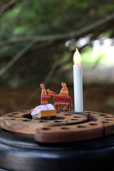 a lit candle sitting on top of a table next to a horse and carriage figurine