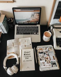 an open laptop computer sitting on top of a desk next to books and headphones