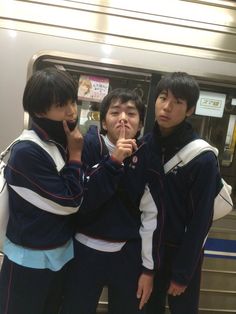 three young men standing next to each other on a subway