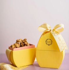 a yellow box filled with cookies next to a bowl full of nuts on top of a table