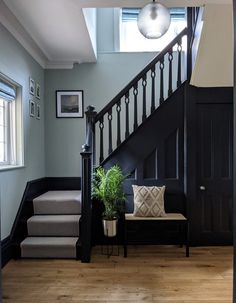 a stair case next to a set of stairs with a plant on the bench in front of it