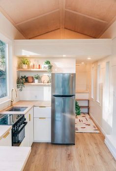 a stainless steel refrigerator in the middle of a kitchen with white cabinets and wood floors