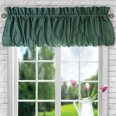 a vase with tulips in front of a window