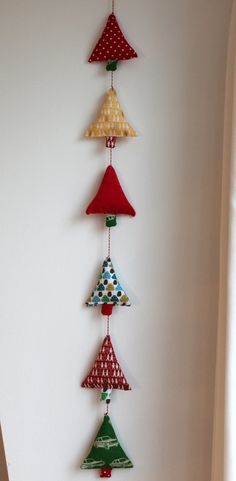 a wind chime hanging from the side of a white wall with red, green and blue decorations