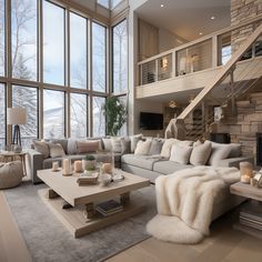 a living room filled with lots of furniture next to tall windows and a stair case