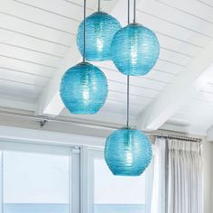 three blue lanterns hanging from the ceiling in a living room next to a large window