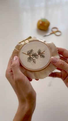 two hands are holding a small embroidered object